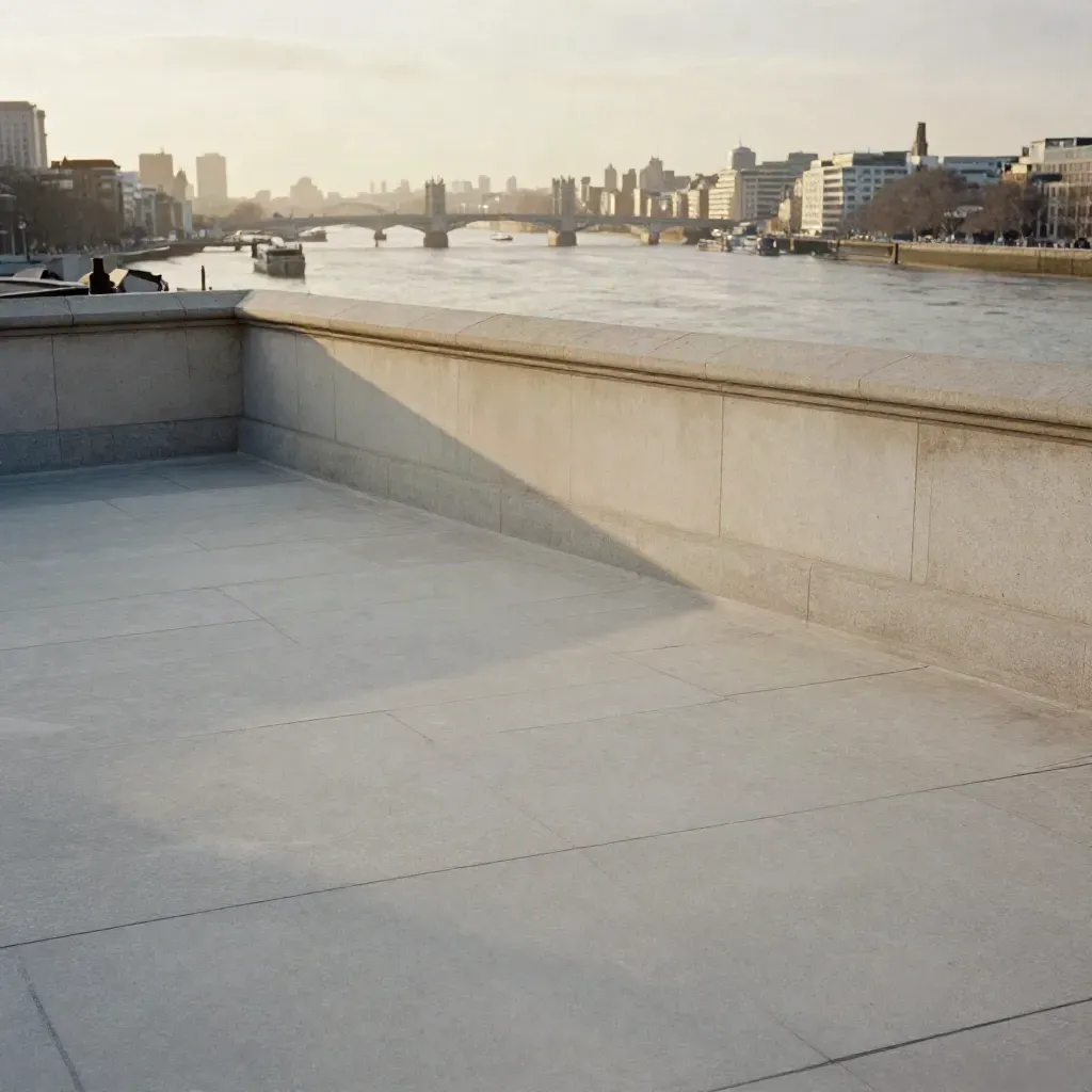 Hazy Thames with distant London skyline above a calm pewter river and pale stone terrace.